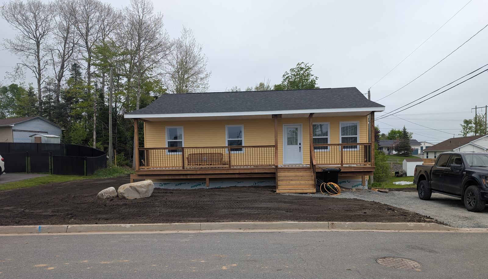 The finished three-bedroom bungalow in Fredericton, yellow siding with a covered front porch