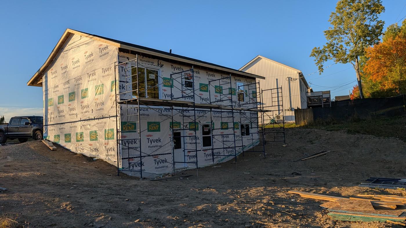 The framed house wrapped in house wrap with scaffolding up