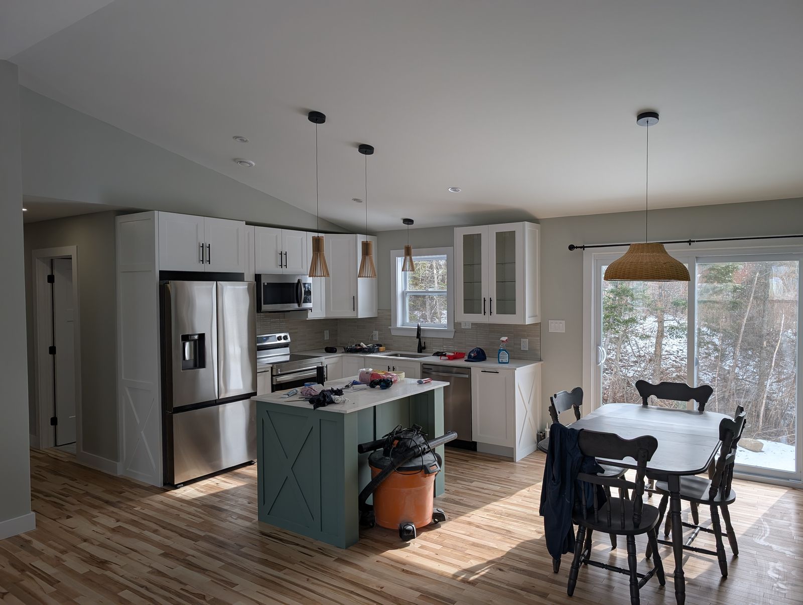 Open kitchen and dining area with vaulted ceiling, white cabinets and a green island