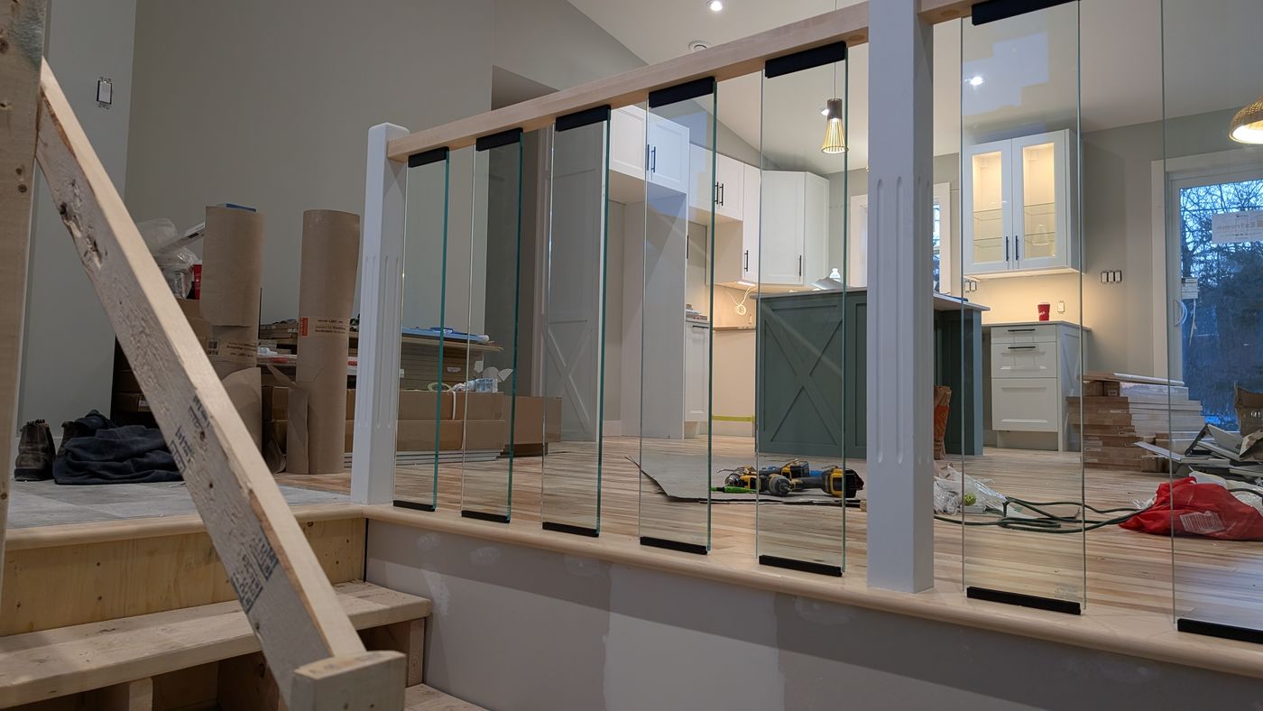 Hardwood floors and a glass stair railing looking through to the kitchen
