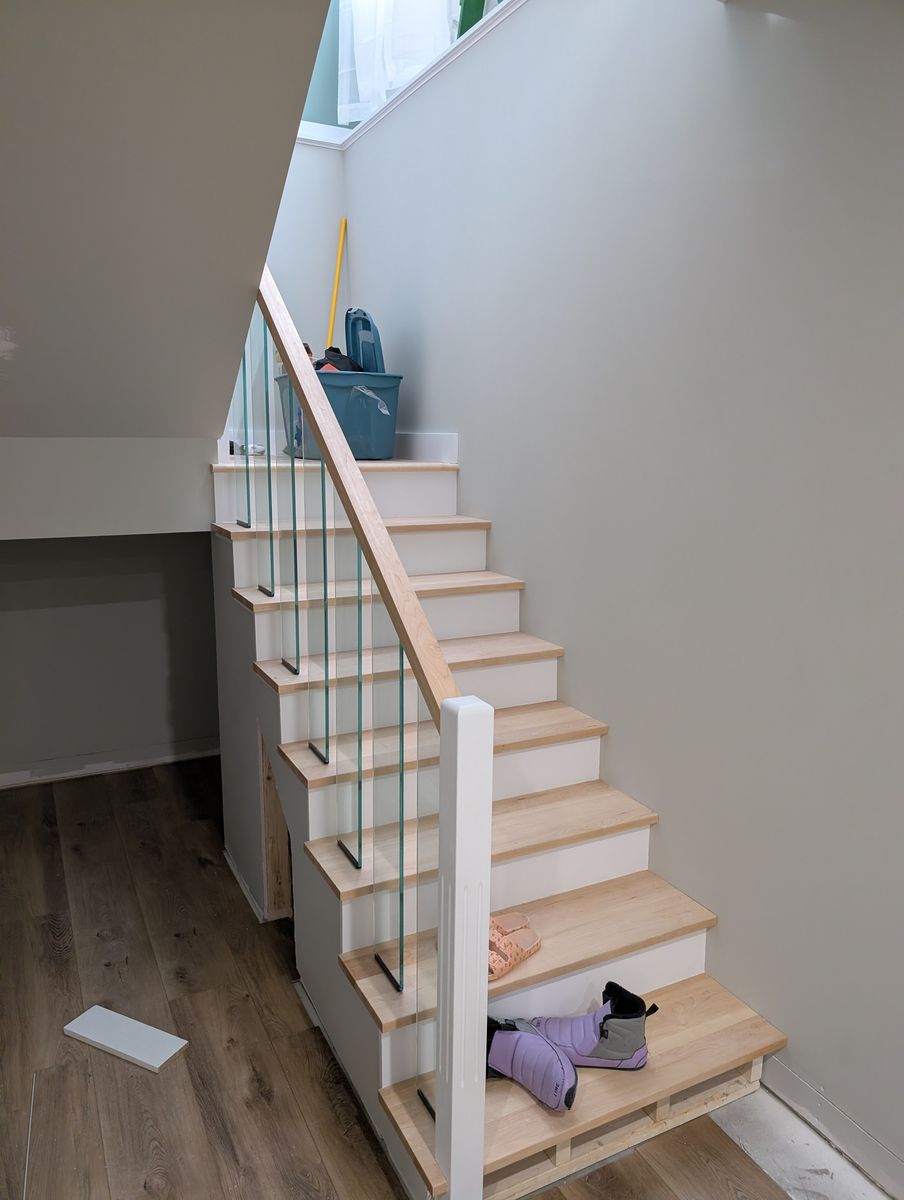 Maple stair treads with a glass railing down to the walkout basement