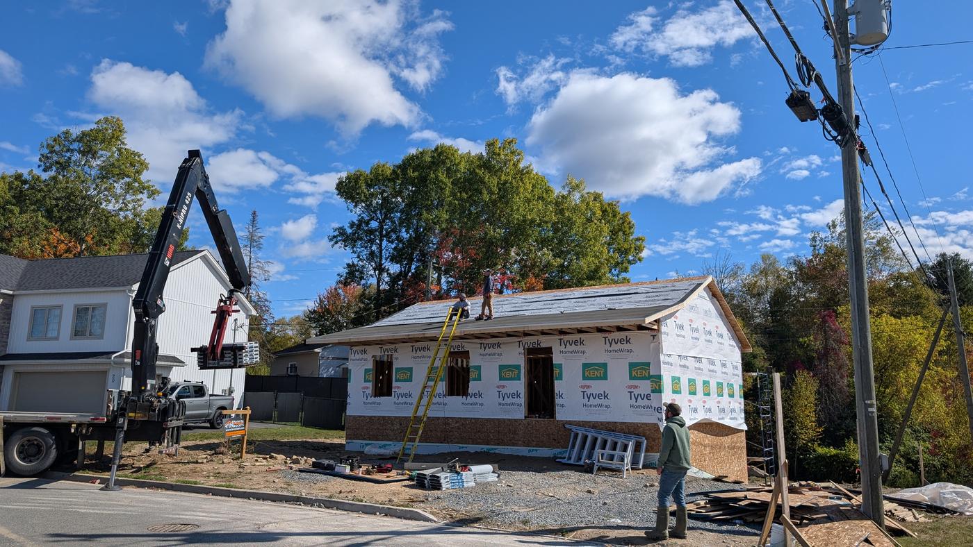 Roof trusses set and the sheathing going on, with the crane still on site